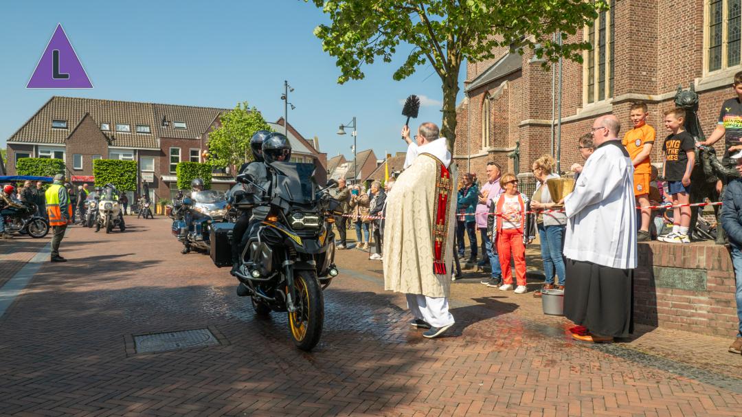 Pastoor Patrick Lipsch zegent brommer- en motorrijders tijdens de motor- en brommerzegening op de Markt in Roggel